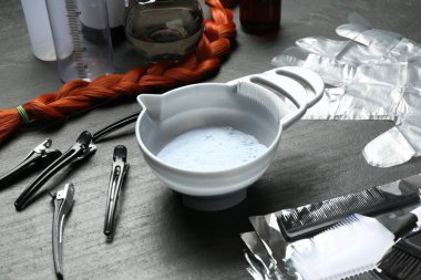 Beyazlatma tozu ve kuaför aletleri siyah masada, yakın plan.