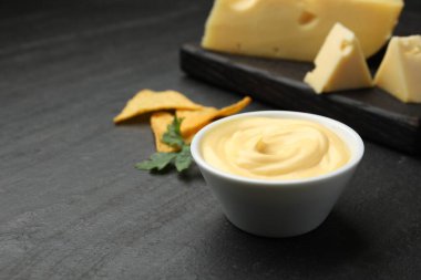 Lezzetli bir peynir sosu, siyah masada nacho cipsi ve maydanoz, yakın plan. Metin için boşluk