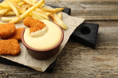 Tabakta nefis peynir sosu, tavuk nugget ve ahşap masada patates kızartması, yakın plan.