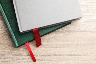 Açık ahşap masa üzerinde kırmızı kurdele yer imleri olan kitaplar, üst manzara. Metin için boşluk