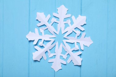 Mavi ahşap zemin üzerinde bir kağıt kar tanesi, üst manzara.