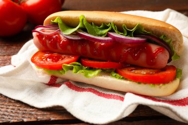 Domatesli, soğanlı, marullu ve ketçaplı lezzetli sosisli sandviç.