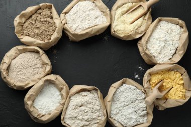 Siyah masada, düz bir zeminde, kağıt torbalarda farklı un tipi çerçeveler. Metin için boşluk