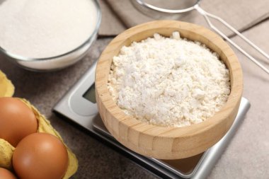 Mutfak terazisi, bir kase un ve gri desenli masa üzerindeki diğer ürünler, yakın plan.