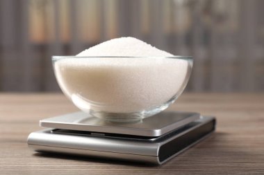 Dijital mutfak terazisi, bir kase şeker, kapalı masa, yakın plan.