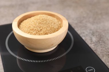 Dijital mutfak terazisi, gri masada bir kase şeker, yakın plan.