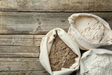 Tahta masadaki poşetlerdeki farklı un türleri, düz yatış. Metin için boşluk