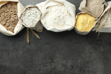 Gri masadaki poşetlerdeki farklı tipte un, düz. Metin için boşluk