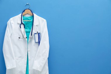 Steteskop ve rozetli doktorun ceketi mavi arka planda. Metin için boşluk