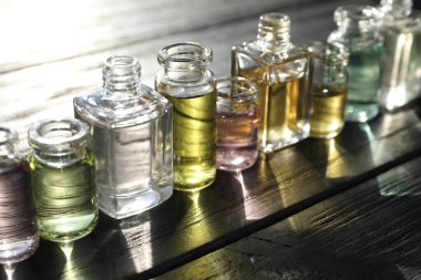 Siyah ahşap arka planda aromatik yağlı parfüm şişeleri, yakın plan.