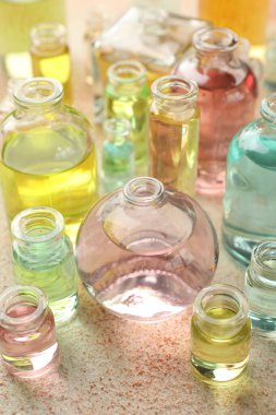 Bej desenli arka planda aromatik yağlı parfüm şişeleri, yakın plan.