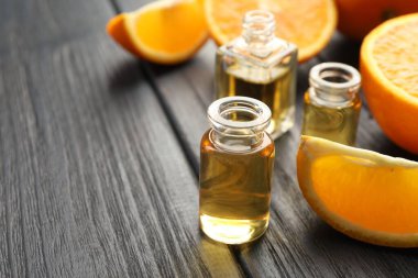 Siyah ahşap masa üzerinde aromatik esanslı yağ ve portakal dilimleri bulunan parfüm şişelerini yakın plan aç. Metin için boşluk