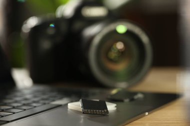 SD hafıza kartları, tutucu, dizüstü bilgisayar ve fotoğraf makinesi ahşap masada, yakın plan.