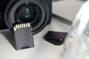 SD hafıza kartları ve fotoğraf makinesi beyaz masada, yakın plan.
