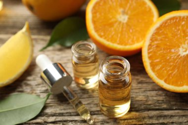 Aromatik esanslı parfüm şişelerini aç. Pipet, portakal ve yapraklar ahşap masada. Yakın plan.