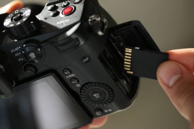Bir adam fotoğraf makinesine SD bellek kartı yerleştiriyor.