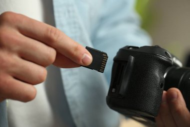 Bir adam fotoğraf makinesine SD bellek kartı yerleştiriyor.