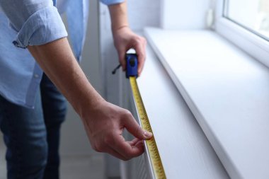 Pencere pervazını bantla ölçen adam, yakın plan.