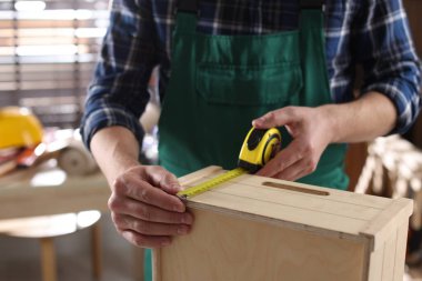 İçerideki bantla ahşap rafı ölçen adam.