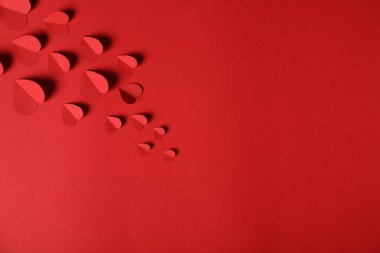 Kırmızı arka planda bir sürü kağıt kalp var. Metin için boşluk