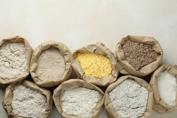 Beyaz masadaki kağıt torbalarda farklı türde un, düz yerde. Metin için boşluk