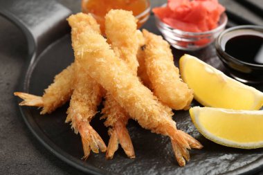 Lezzetli tempura karidesleri, limon, zencefil ve soslar gri desenli masada, yakın plan.