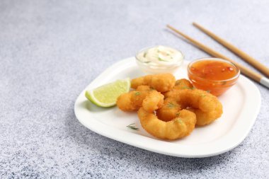 Lezzetli tempura karidesleri, limon ve soslar gri desenli masa, yakın plan. Metin için boşluk