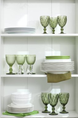 İçerideki raflarda temiz bardak ve tabaklar var.