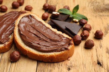 Lezzetli fındıklı tostlar, çikolata parçaları ve fındıklar ahşap masada, yakın plan.