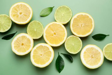 Soluk yeşil arka planda limon ve limon dilimleri, düz uzanmış.