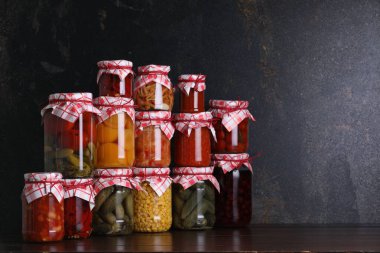 Ahşap masada farklı turşu ürünleri olan bir sürü kavanoz, metin için yer.