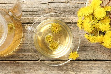 Tazeleyici karahindiba çayı ve çiçekler ahşap masada, düz yatıyordu.