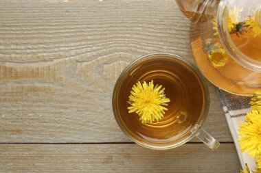 Tahta masada karahindiba çayı ve çiçekler serinletiyor. Metin için boşluk