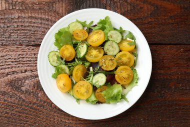 Tahta masanın üstünde sarı domatesli taze salata, üst manzara.