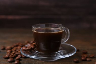 Cam bardakta Aromatik kahve ve ahşap masada fasulye, yakın plan.