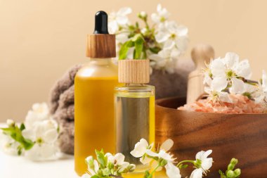 Bej masa üzerinde kozmetik ürünleri ve güzel çiçeklerle kaplıca kompozisyonu, yakın plan.