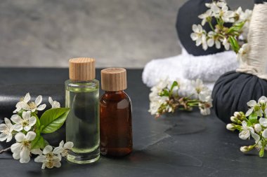 Siyah desenli masa üzerinde kozmetik ürünleri ve güzel çiçeklerle kaplıca kompozisyonu, yakın plan.