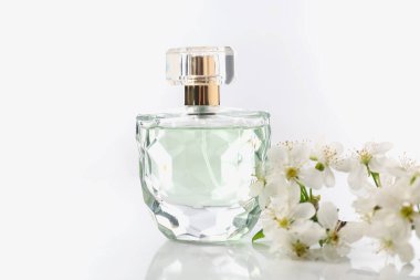 Aromatik parfüm ve beyaz arka planda güzel çiçekler, yakın plan.