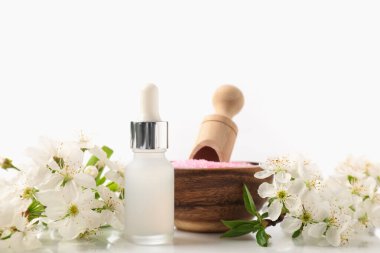 Beyaz arka planda kozmetik ürünleri ve güzel çiçeklerle kaplıca kompozisyonu, yakın plan