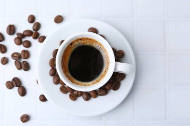Aromatik kahve fincanda ve fasulye beyaz fayanslı masada, düz yerde. Metin için boşluk