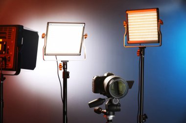 Renkli arka planda profesyonel ışıklandırma ekipmanı ve kamera