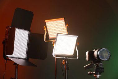 Renkli arka planda profesyonel ışıklandırma ekipmanı ve kamera