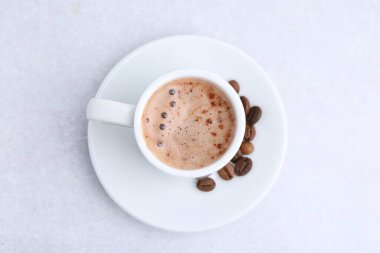 Aromatik kahve fincanda, fasulye ve çay tabağı ışık masasında, üst manzara.