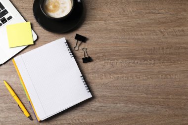 Not defteri, yapışkan not, kalem, cilt klipsleri, sehpada kahve ve dizüstü bilgisayar, düz yatak. Metin için boşluk