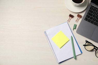 Not defteri, yapışkan not, kalem, gözlük, ataç ve dizüstü bilgisayar tahta masaya, düz yatıyordu. Metin için boşluk