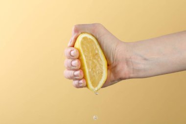 Sarı arka planda limon sıkan kadın, yakın plan.