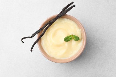 Lezzetli vanilyalı puding, nane ve kapsüller açık gri masada.