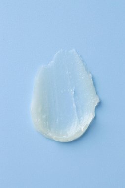 Açık mavi arkaplanda nemlendirici dudak kremi, üst görünüm