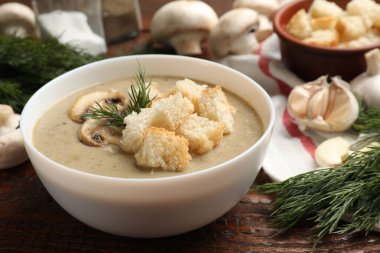 Lezzetli mantar kremalı çorba, kızarmış ekmek, dereotu ve ahşap masa malzemeleri, yakın plan.