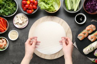 Koyu gri masada nefis börek yapan bir kadın.
